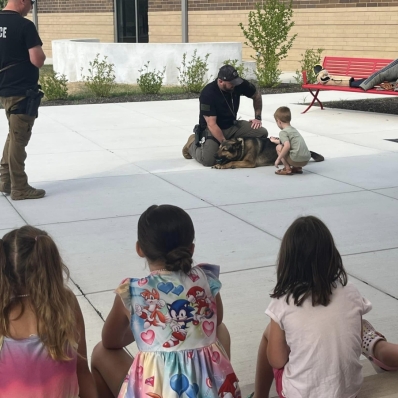 Children at Safety Town watching a student pet a K9 officer